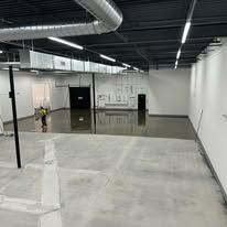 A large empty room with a concrete floor and white walls.