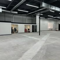 A large empty warehouse with a concrete floor and a balcony.