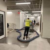 A man is using a vacuum cleaner to clean the floor of a building.