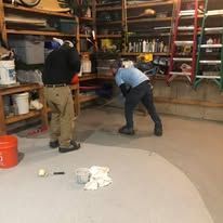 Two men are working on a carpet in a garage.