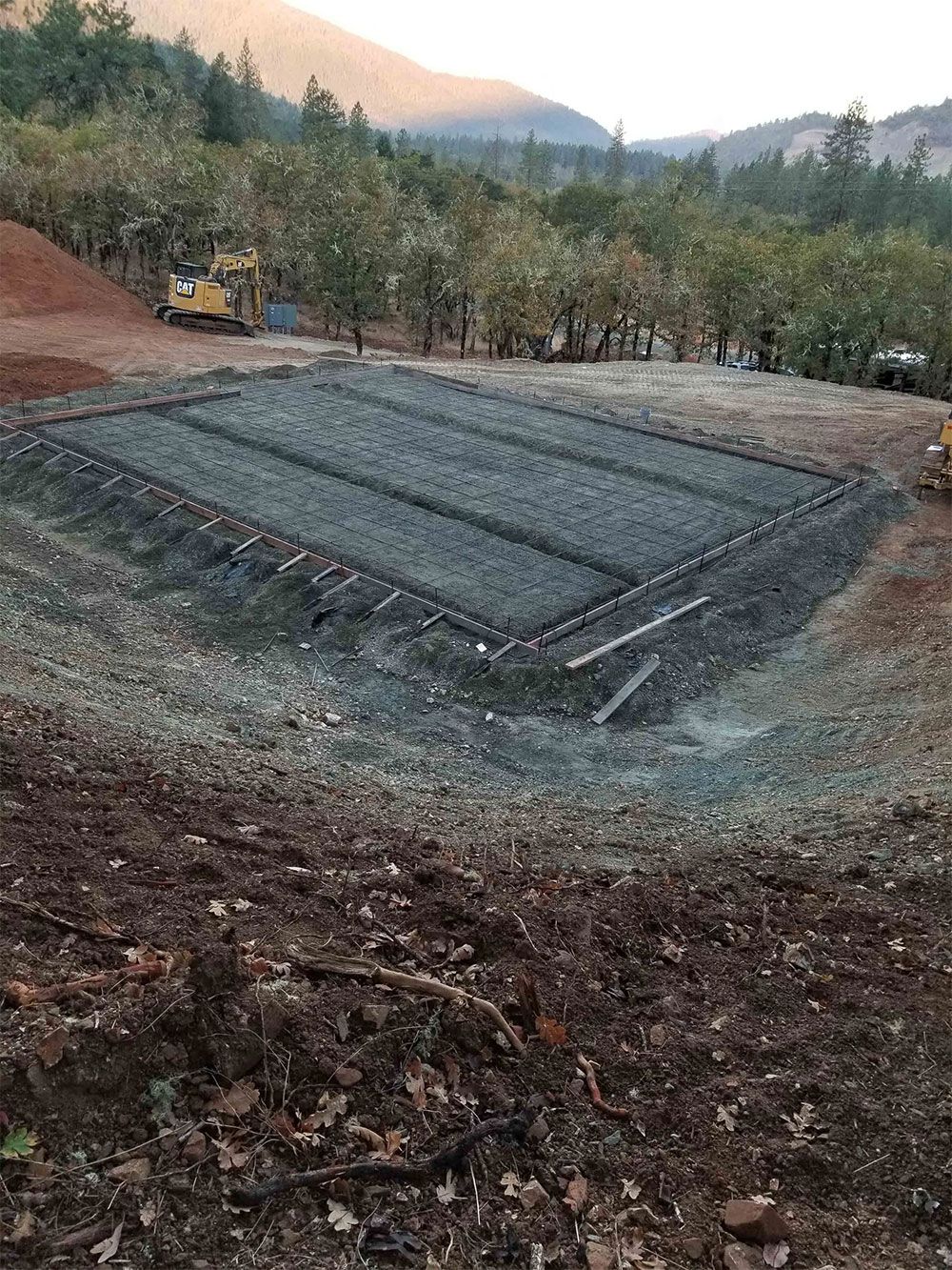 A rectangular gravel leach field under construction in a rural setting, with heavy equipment visible.