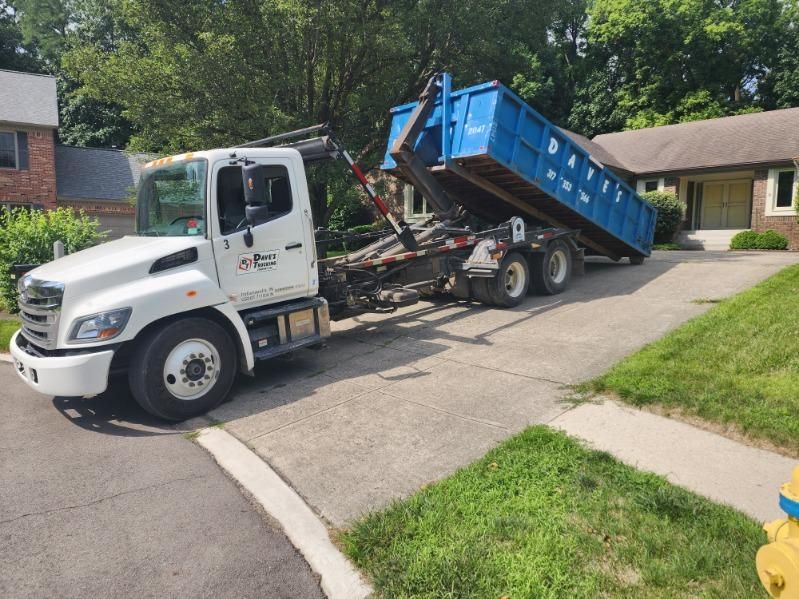 A dumpster truck is parked in front of a house.
