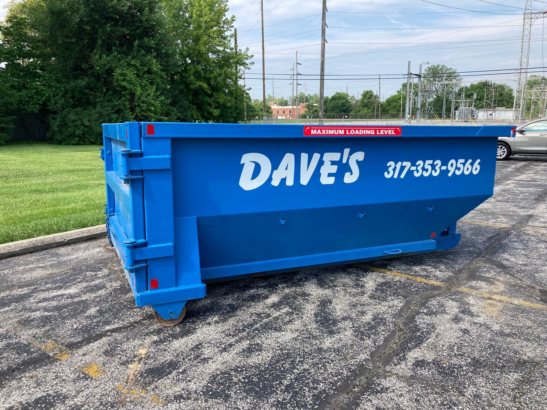 A blue dumpster is parked in a parking lot.