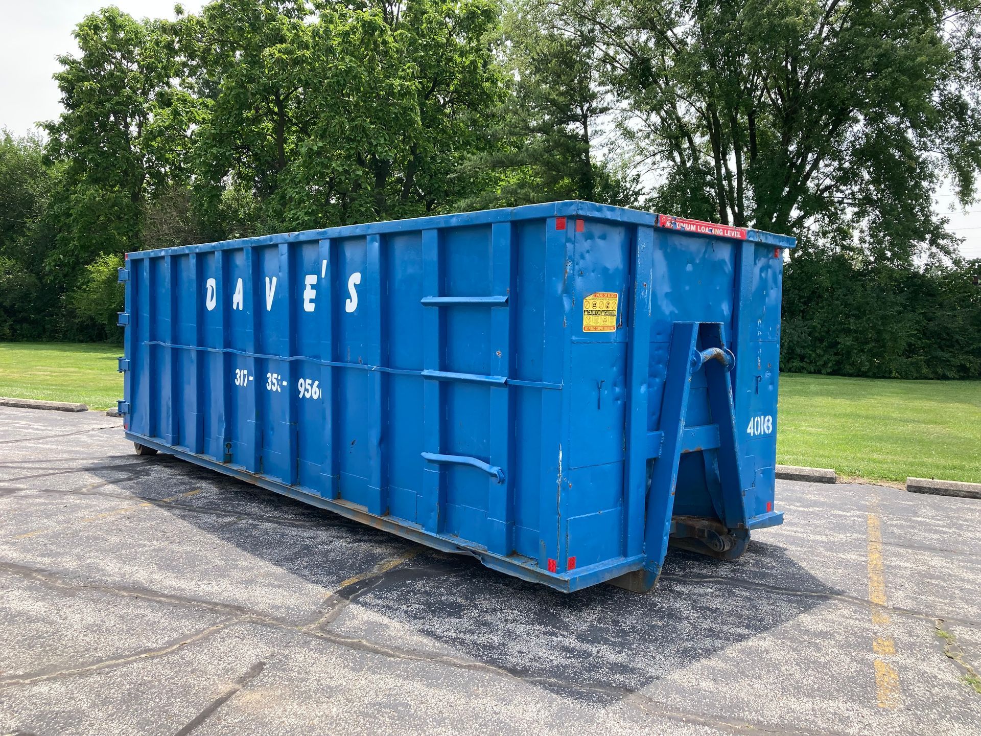A large blue dumpster is sitting in a parking lot.