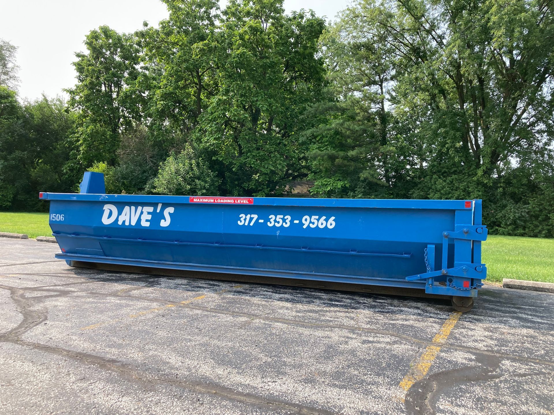 A blue dumpster is parked in a parking lot.