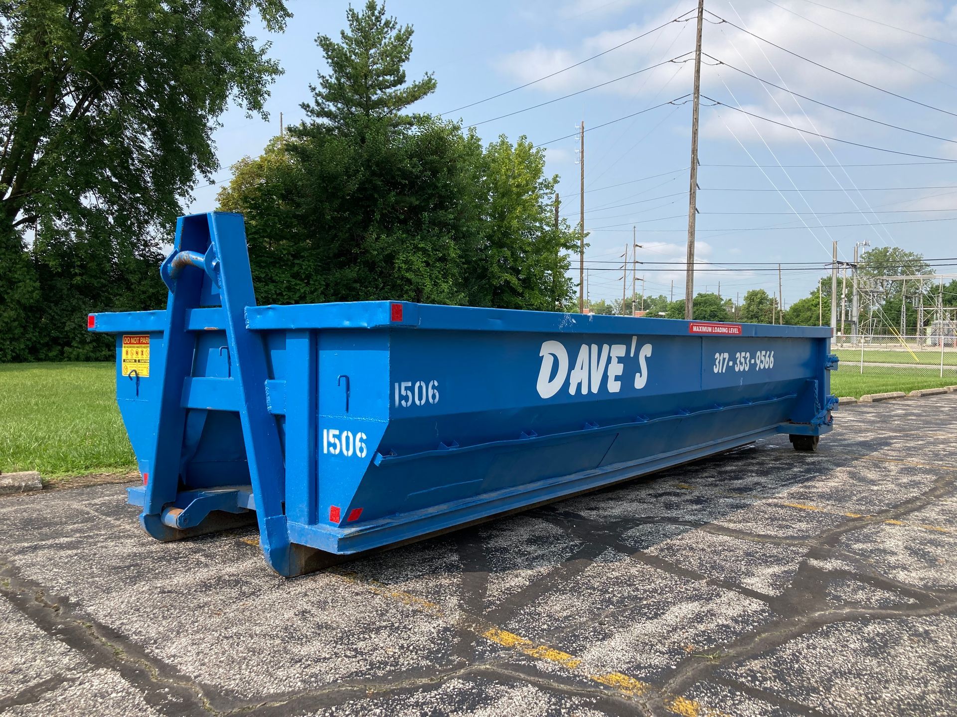 A large blue dumpster is parked in a parking lot.