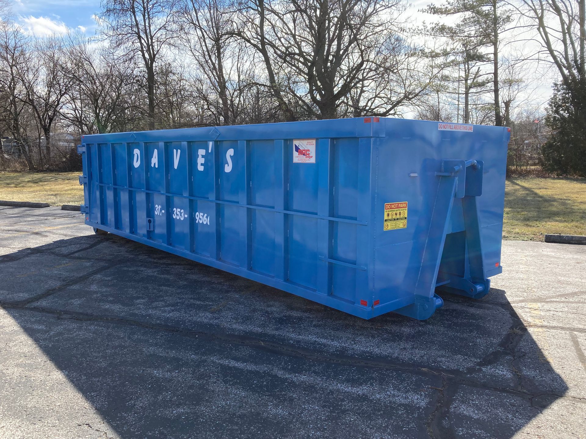 A large blue dumpster is sitting in a parking lot.