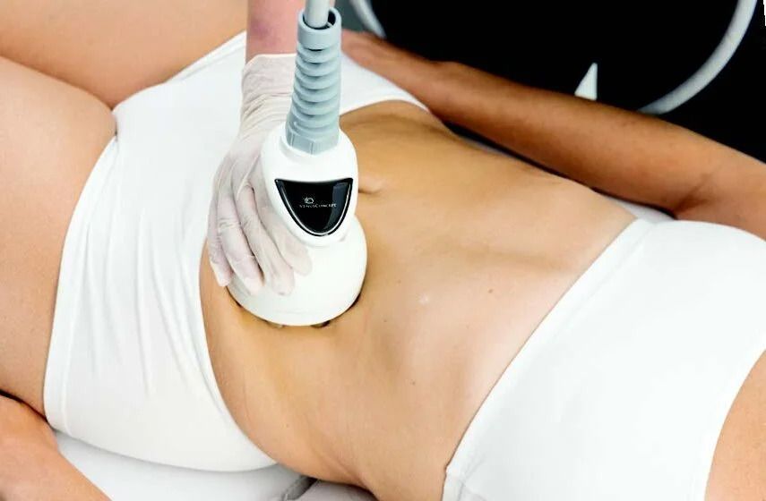Person receiving abdominal fat reduction treatment with a handheld device, white setting.