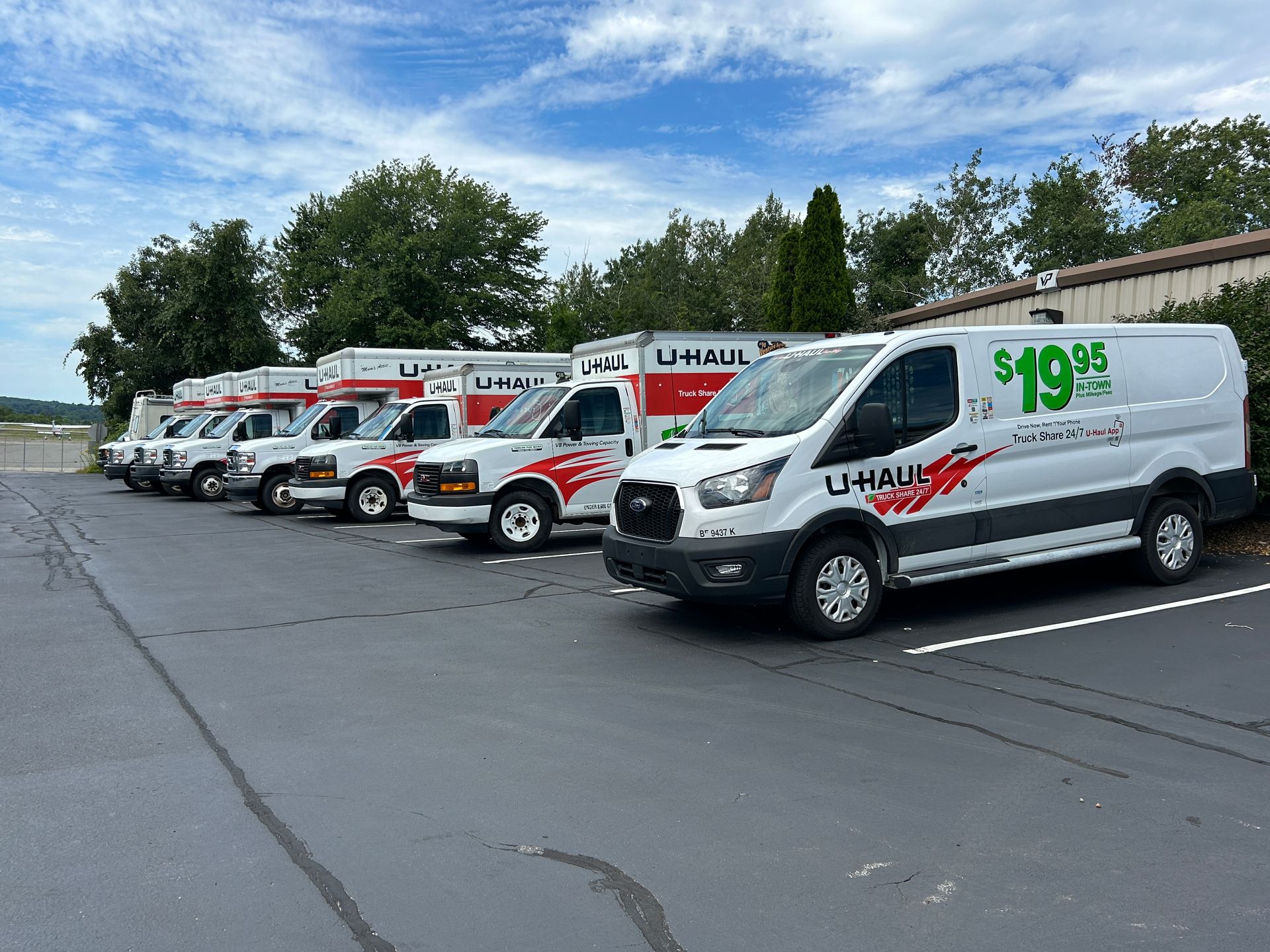 U-Haul rental vans lined up in a parking lot under a cloudy sky