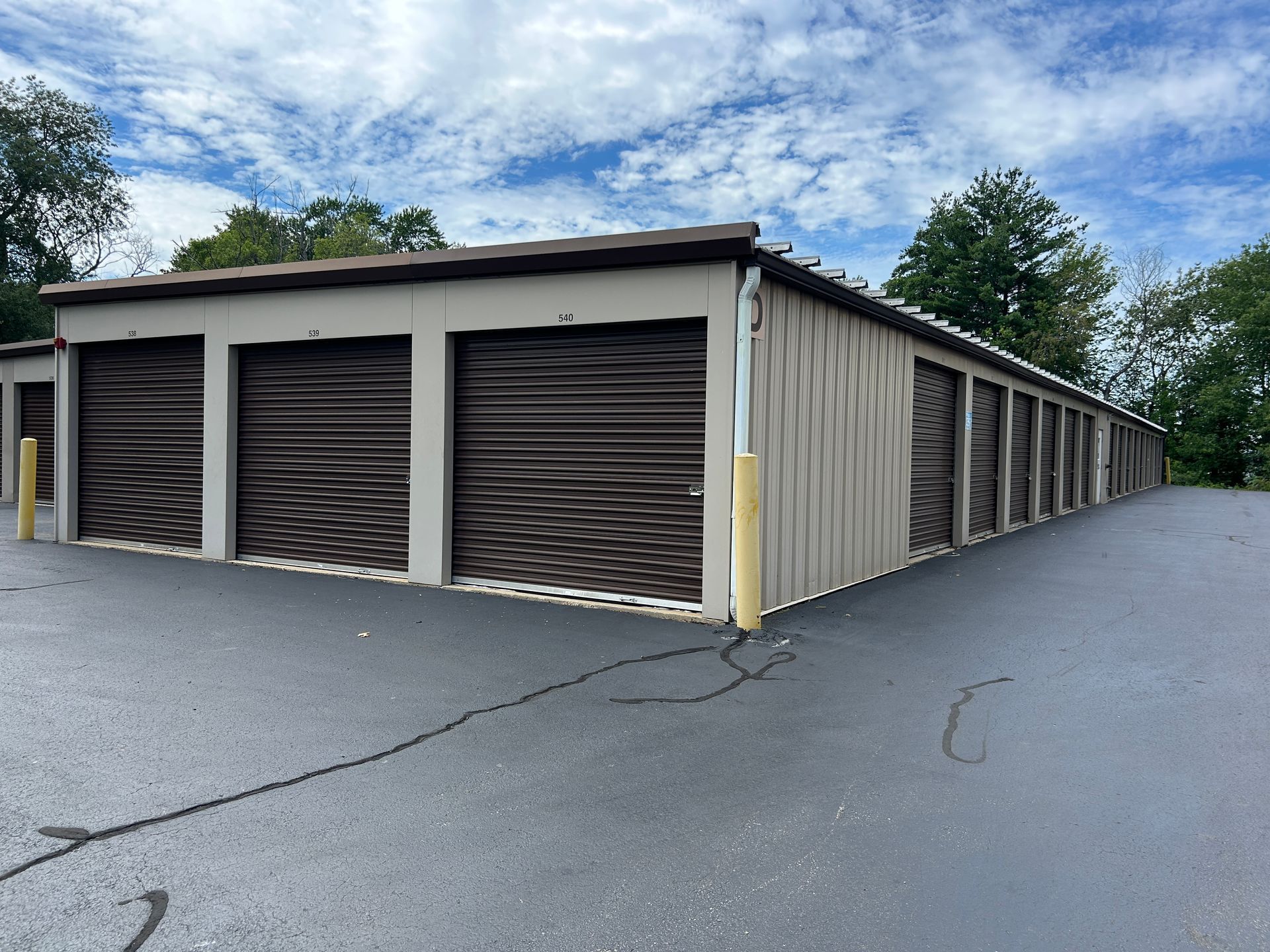 Storage unit building with beige walls and brown roll-up doors in a paved lot