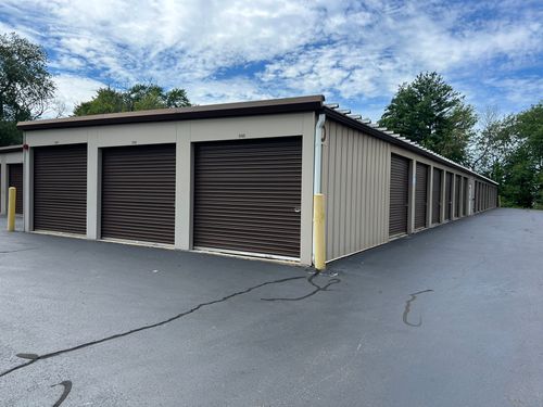 Storage unit building with beige walls and brown roll-up doors in a paved lot