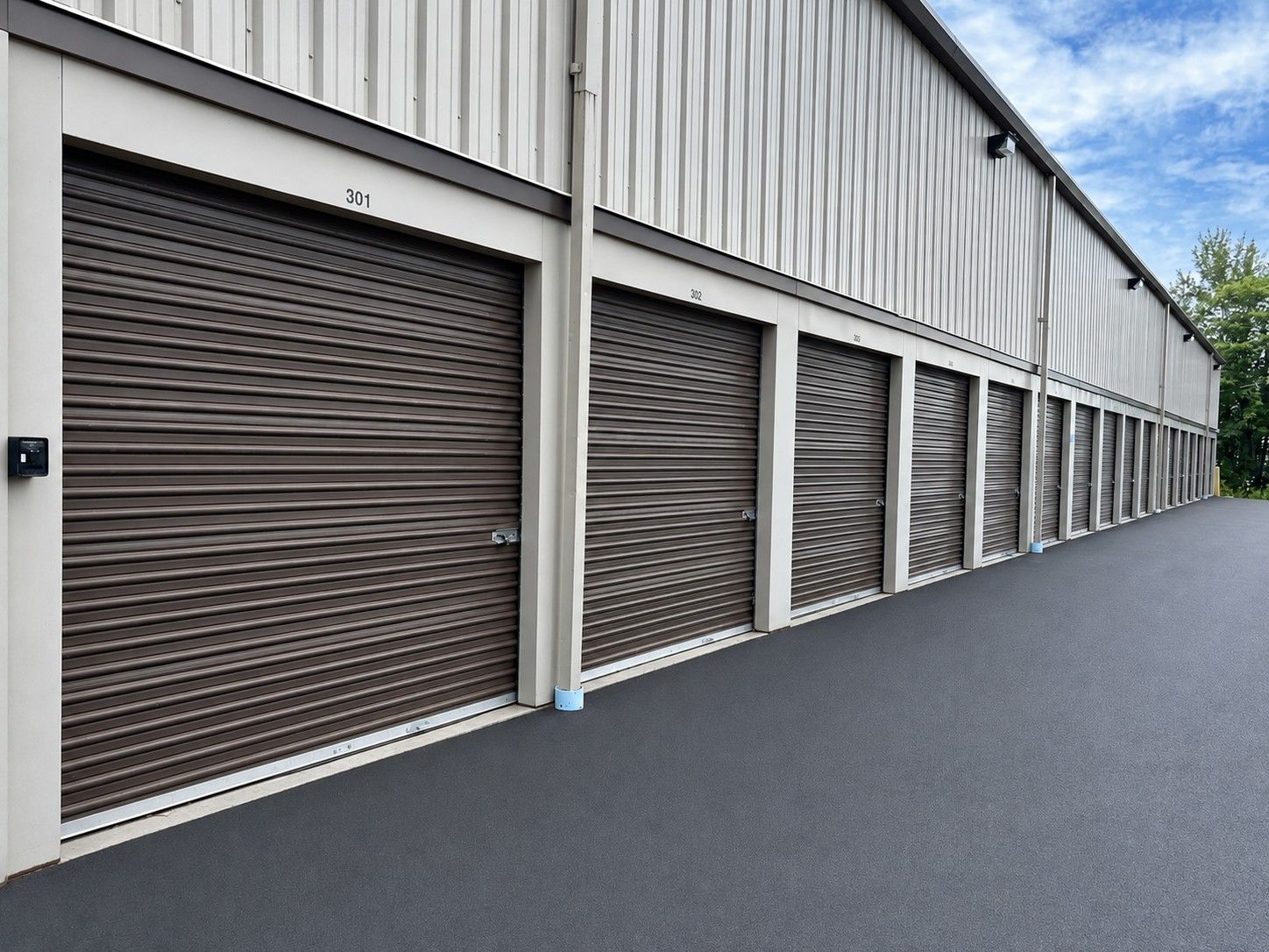 Row of closed brown storage unit doors beside a paved alley