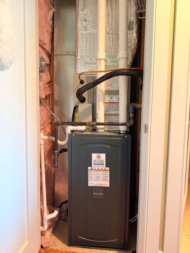 Residential HVAC furnace installed in a narrow utility closet with exposed ductwork and wiring.
