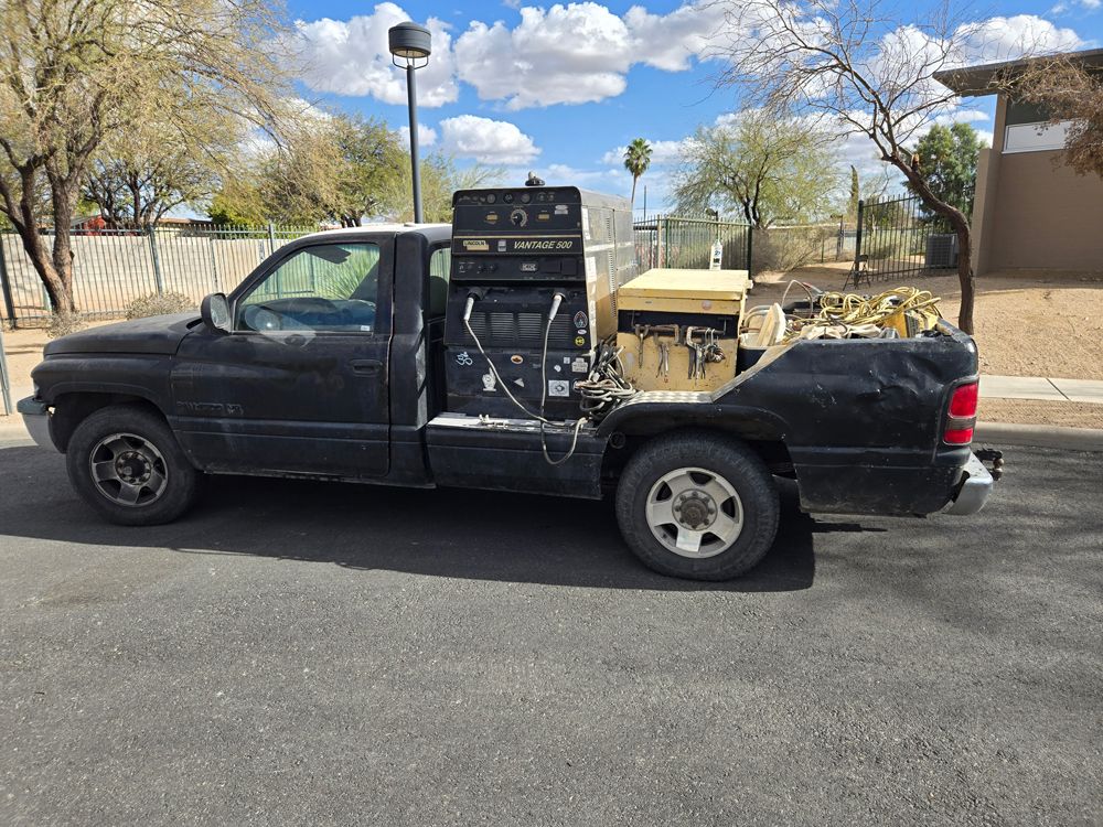 A black truck with a toolbox in the back is parked on the side of the road.