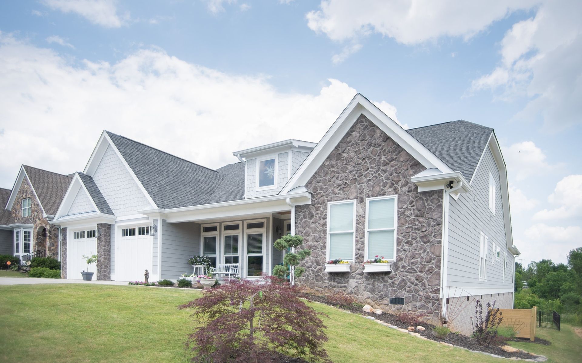 A large house with a gray roof is sitting on top of a lush green hill.