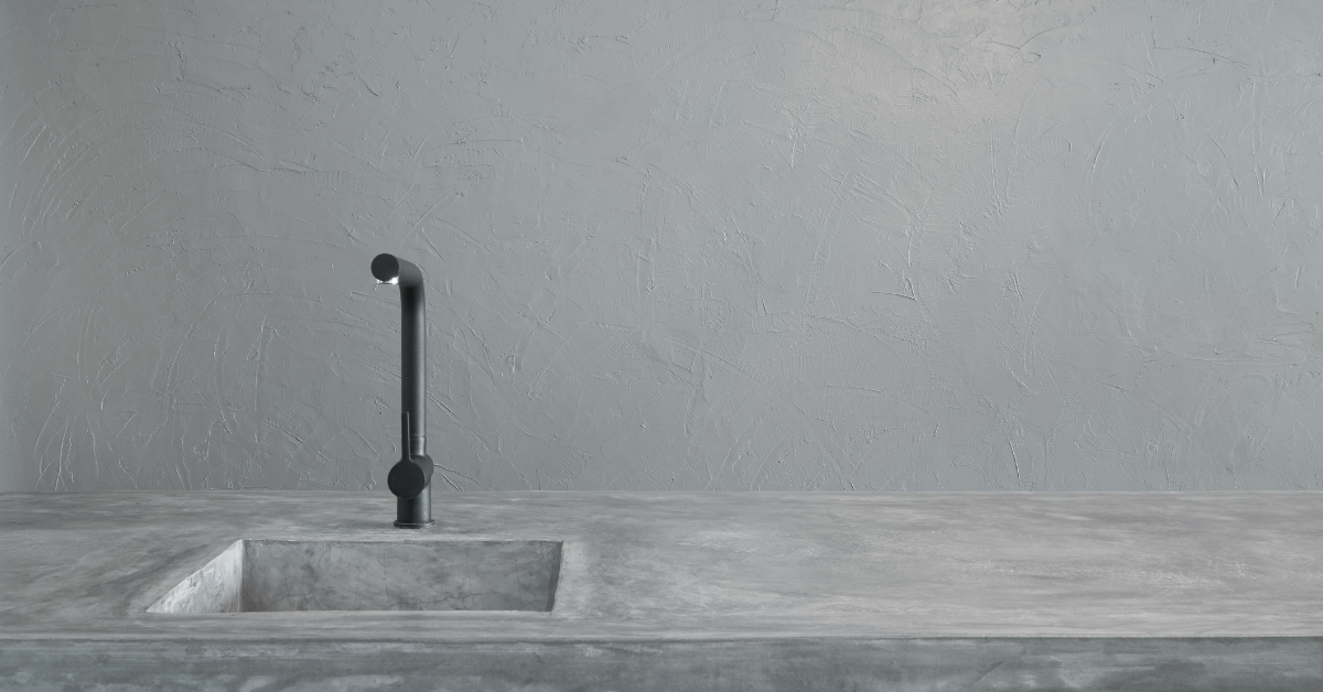 Minimal gray kitchen sink with black faucet against a plain gray wall.