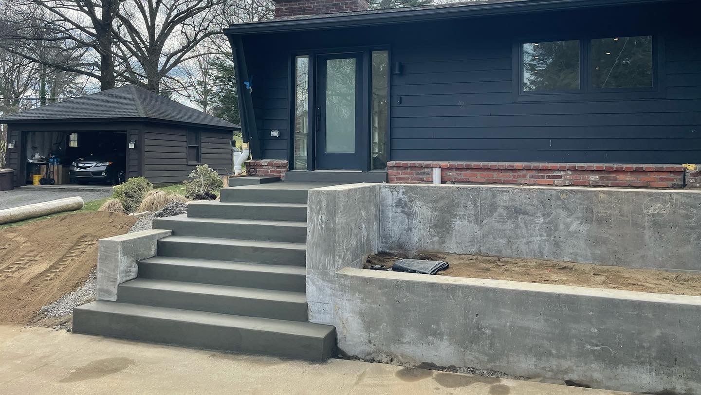 Concrete steps leading to a dark house with a raised front entry and retaining wall