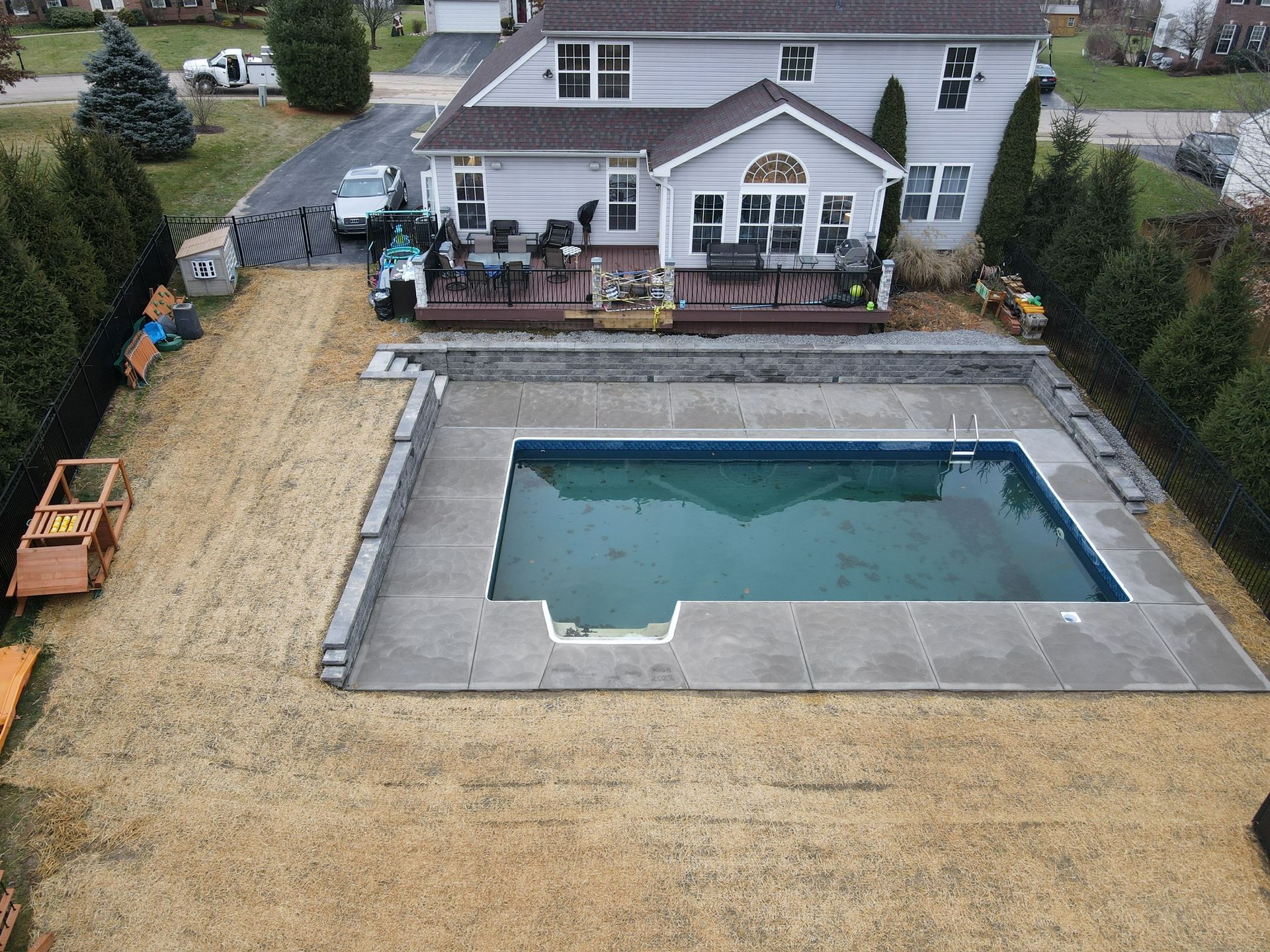 Backyard with an in-ground pool, patio furniture, and a house with a deck behind it.