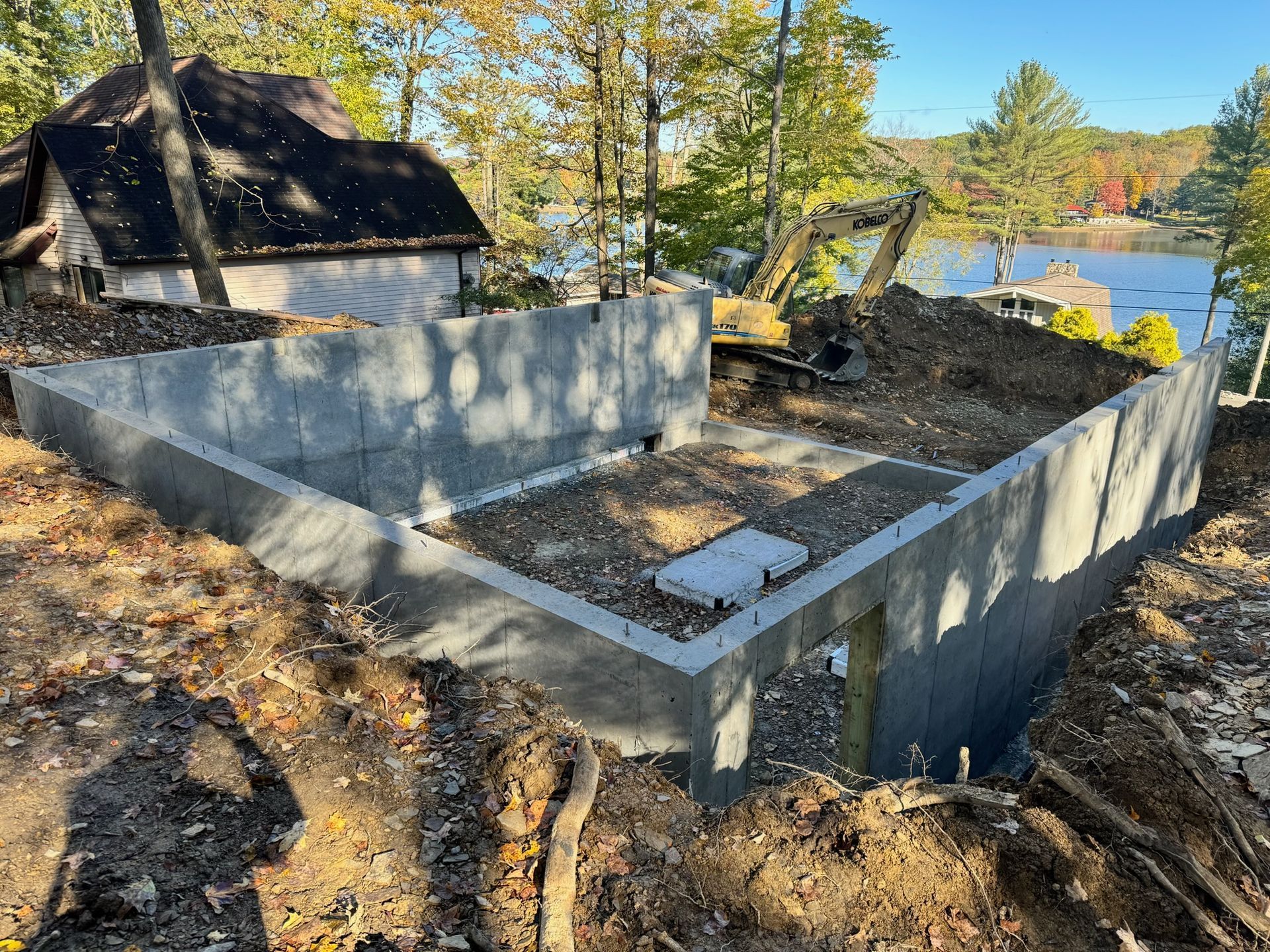 Concrete foundation walls at a wooded lakeside construction site in autumn