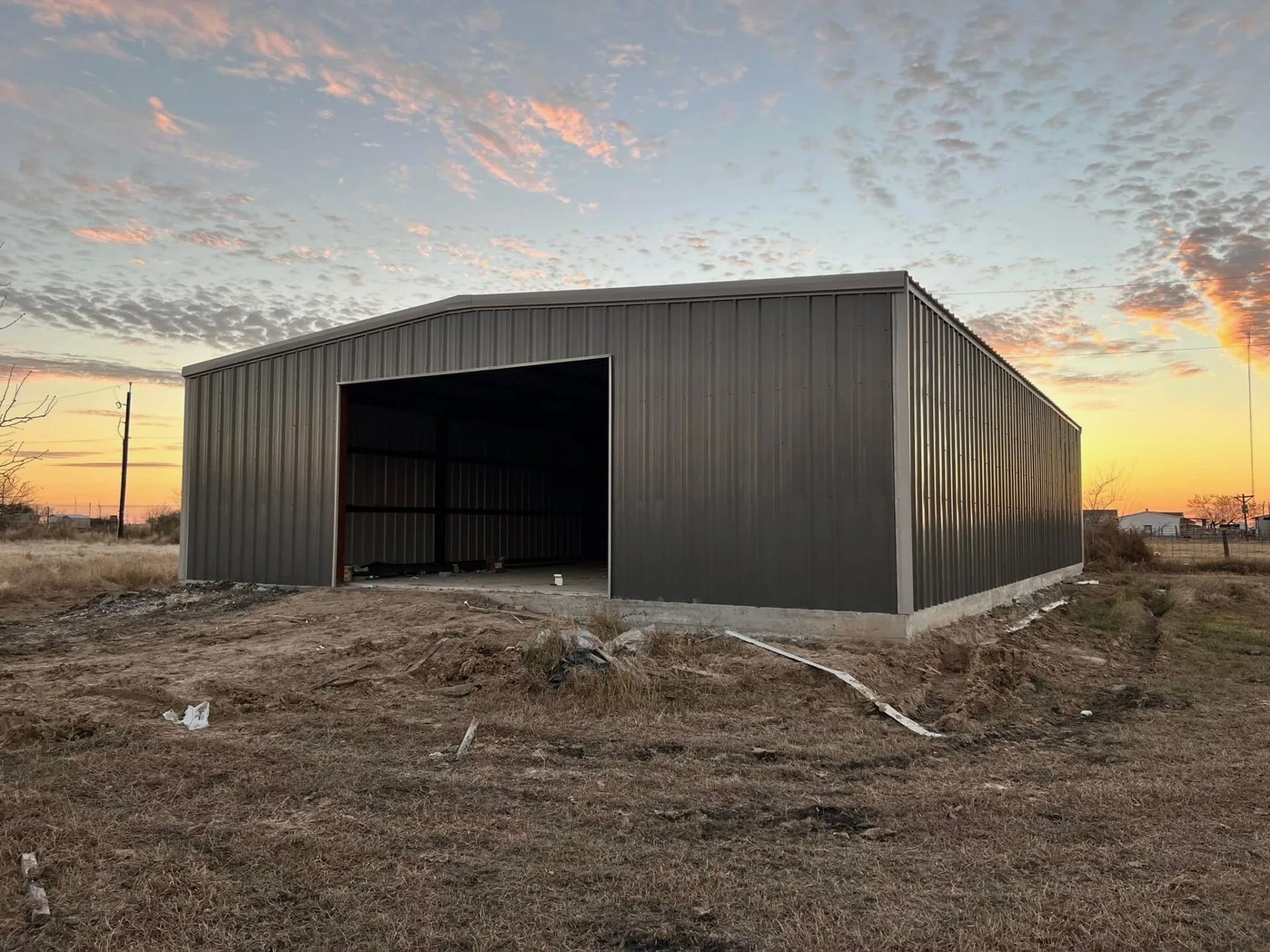 Metal shed with open doorway in a dry field at sunset