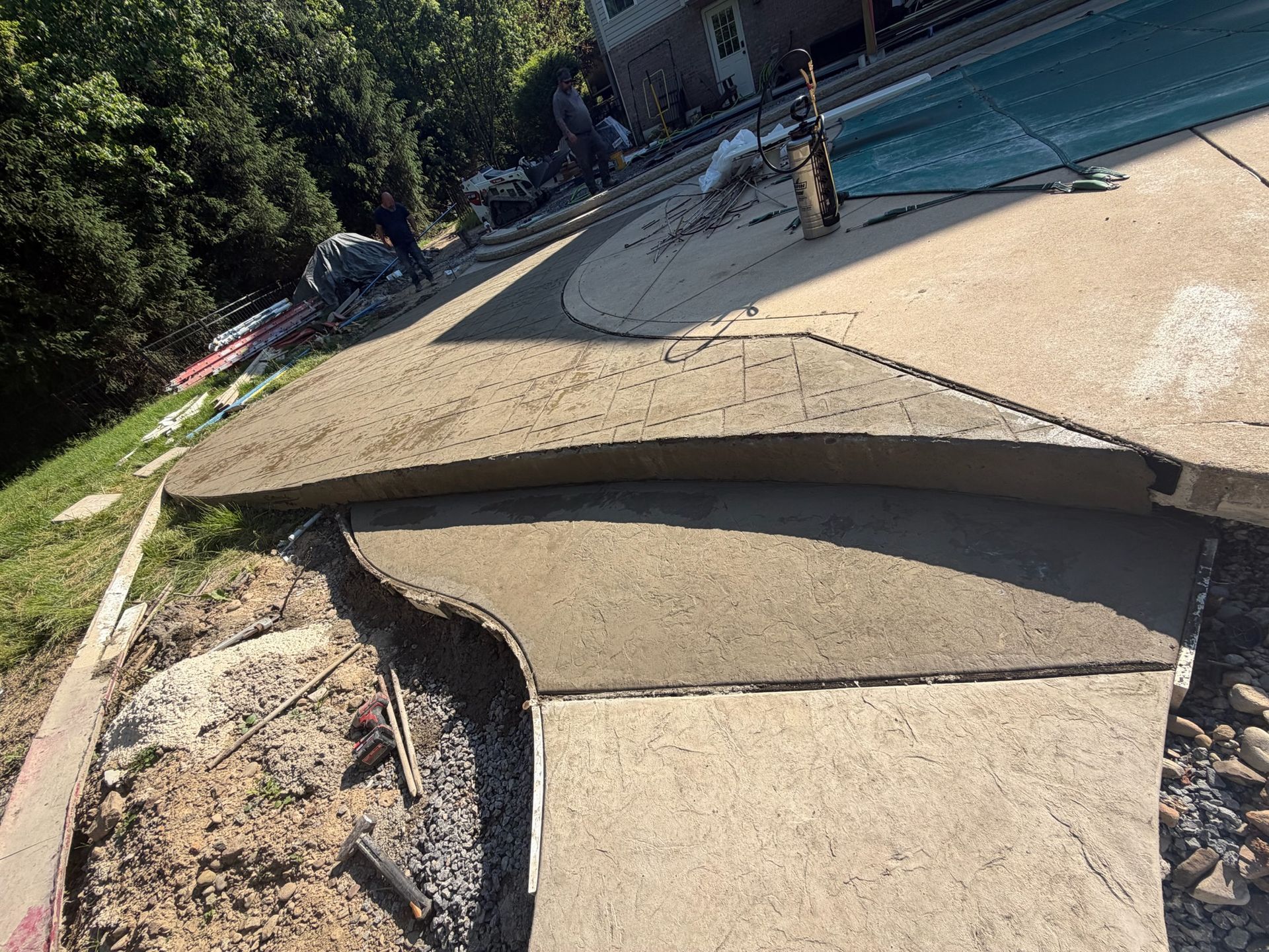 Collapsed concrete walkway beside a pool, with a large broken slab and exposed dirt.
