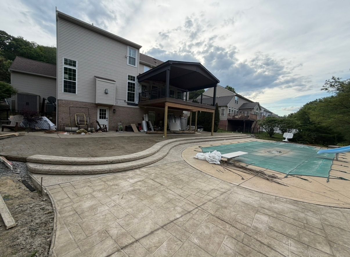 Backyard with a pool, concrete patio, and modern house under cloudy skies