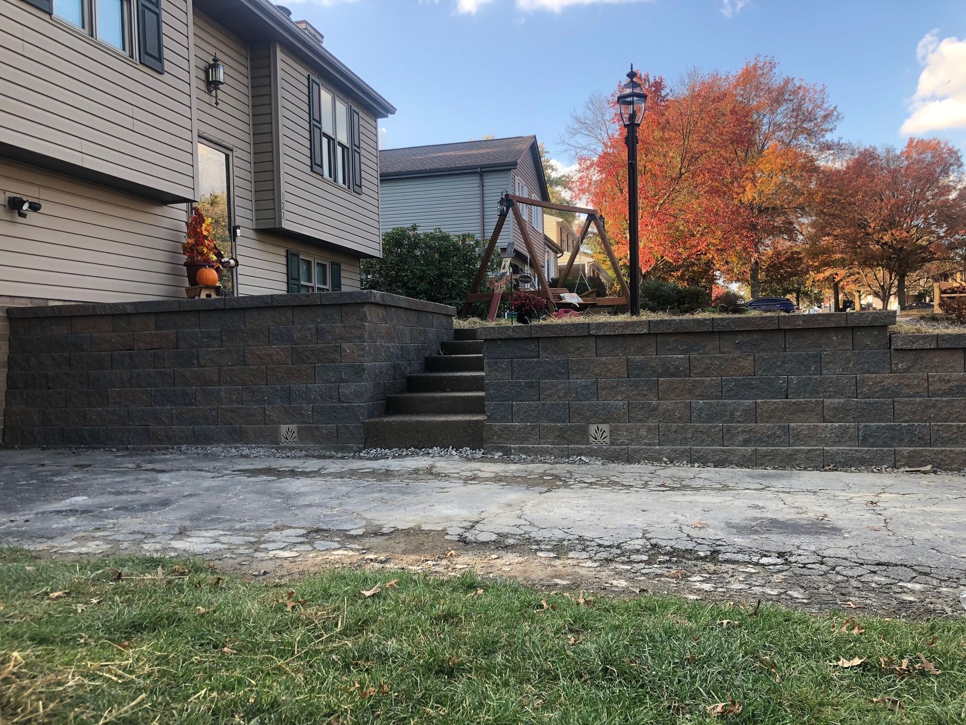 Stone steps beside a house in autumn, with fallen leaves and orange trees in the background