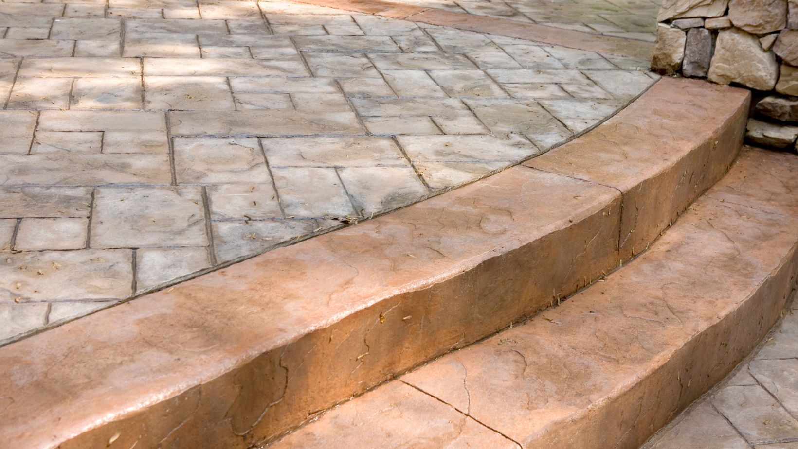Curved stone steps beside a paved patio