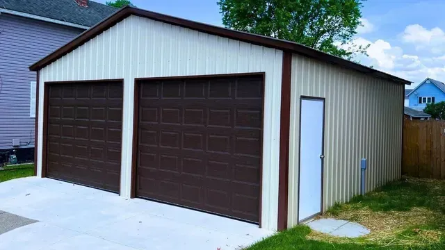 Two-car detached garage with brown doors, white trim, and a side entry door beside a grassy yard.