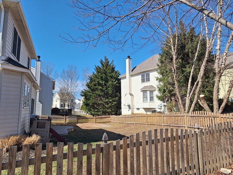 Backyard view of homes with a wooden fence and bare trees under a clear blue sky.