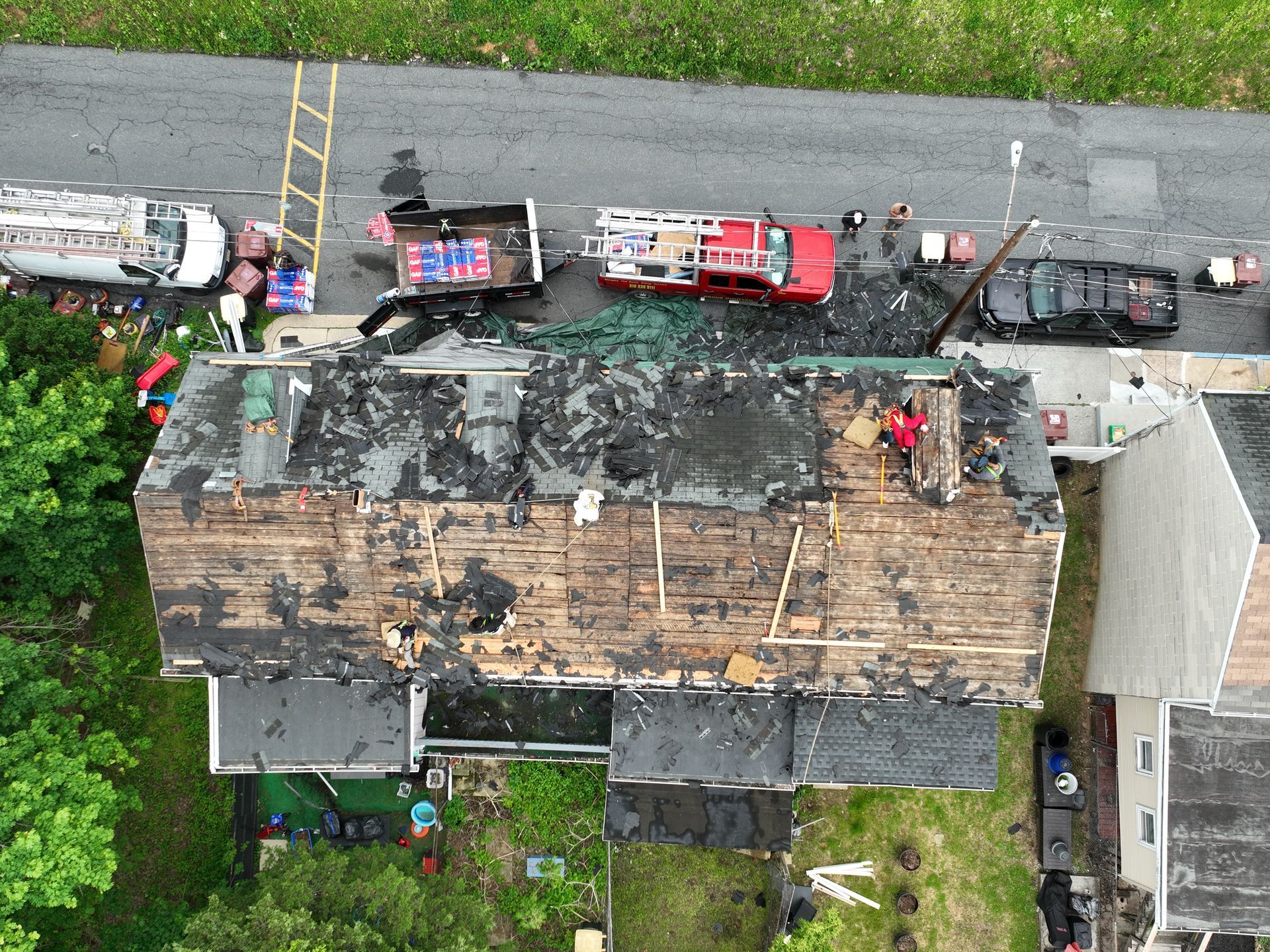 Aerial view of firefighters and fire trucks surrounding a heavily burned house roof