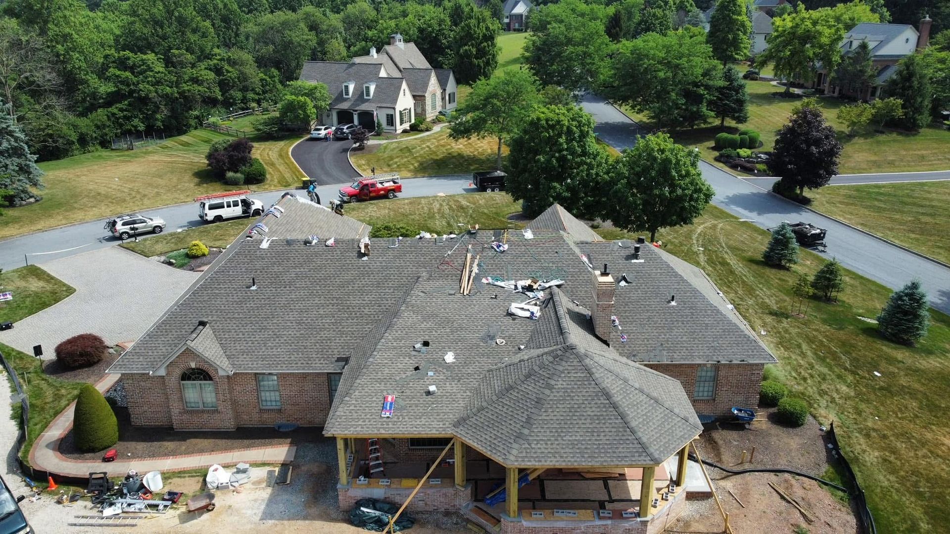 Aerial view of a house under construction with workers on the roof in a suburban neighborhood