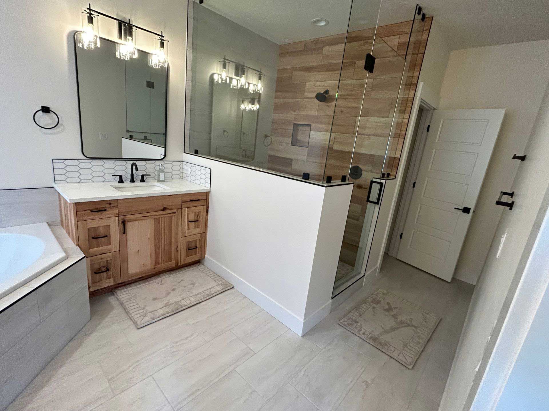 a bathroom with a tub, sink, mirror, and walk-in shower