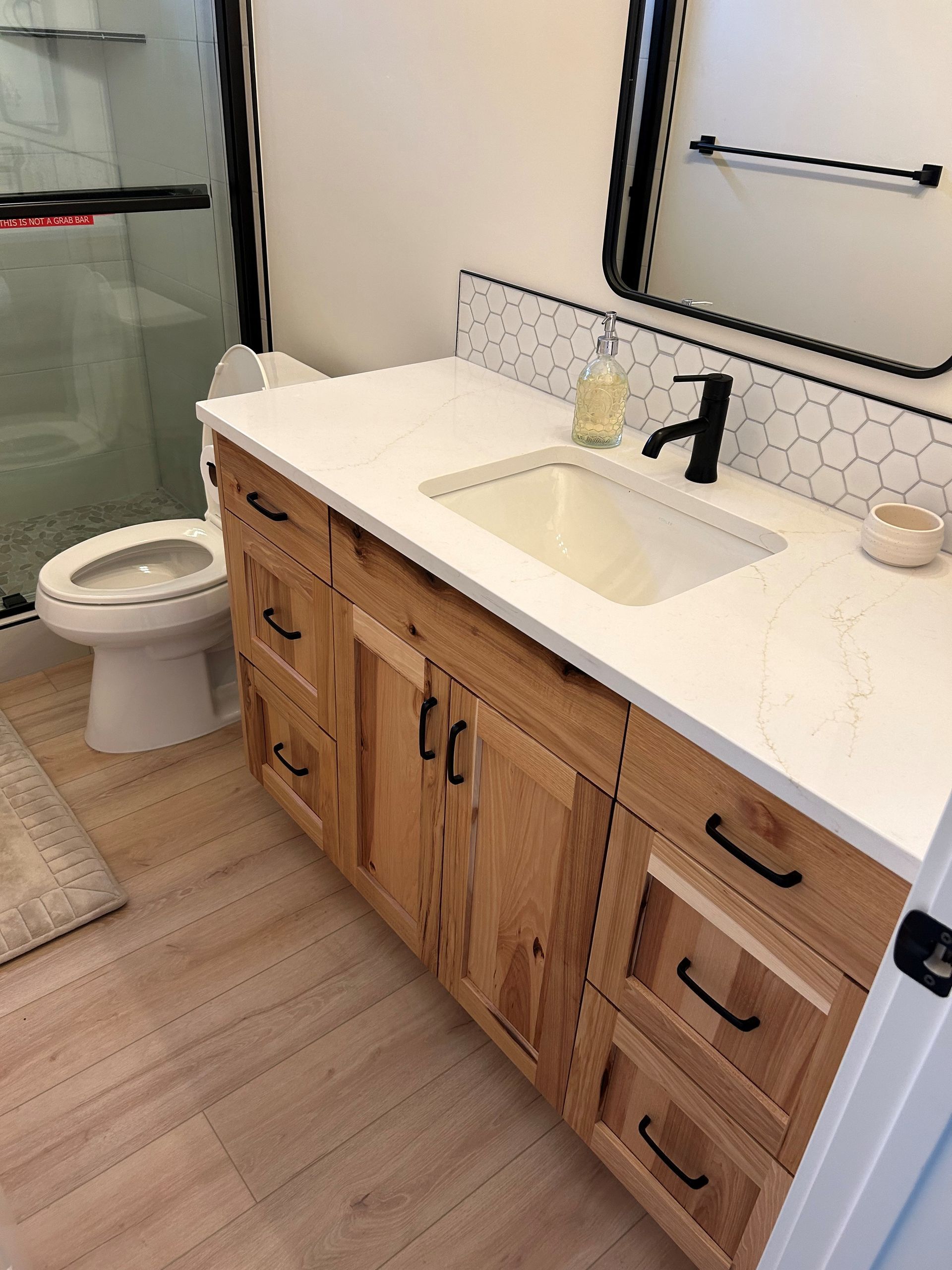a bathroom with a sink, toilet, and mirror.