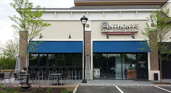 A restaurant with a blue awning and tables and chairs in front of it.