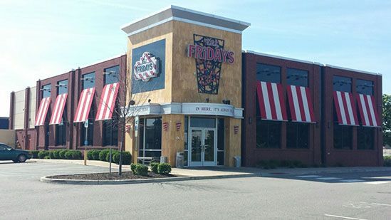 A large brick building with red and white awnings on the windows.