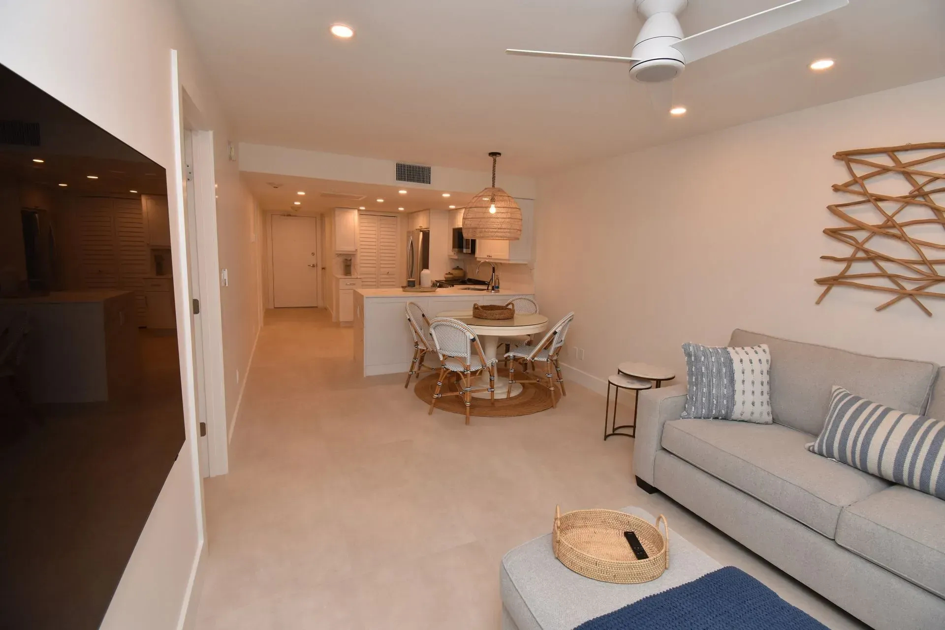 A modern living space with a sofa, dining area, and kitchen. Neutral colors and beachy decor.