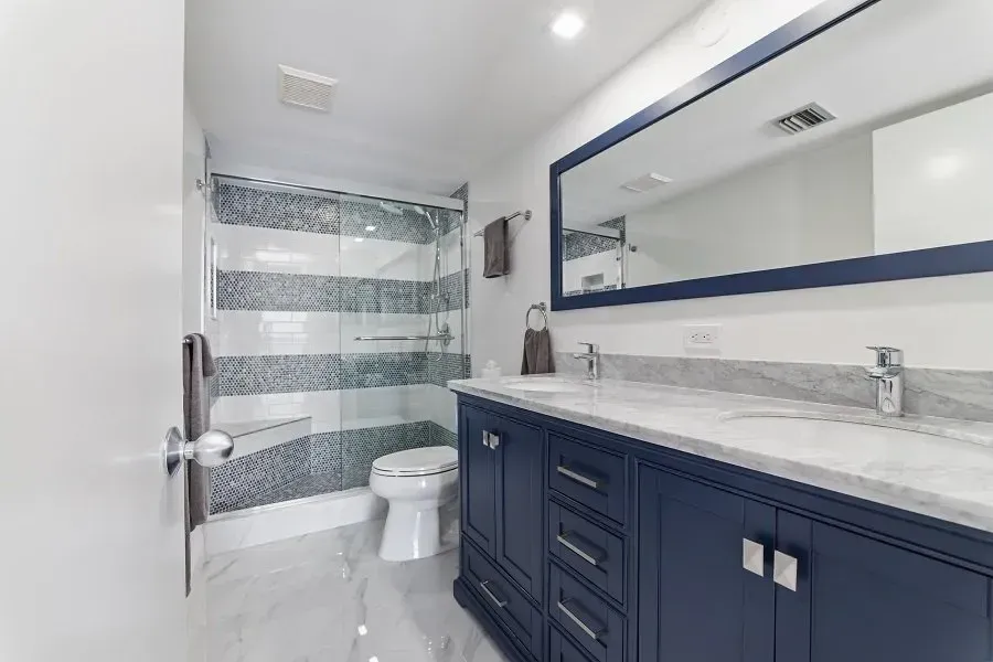 Blue and white bathroom with a vanity, toilet, and shower.