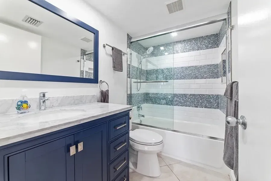 Blue and white bathroom with vanity, shower, and toilet.