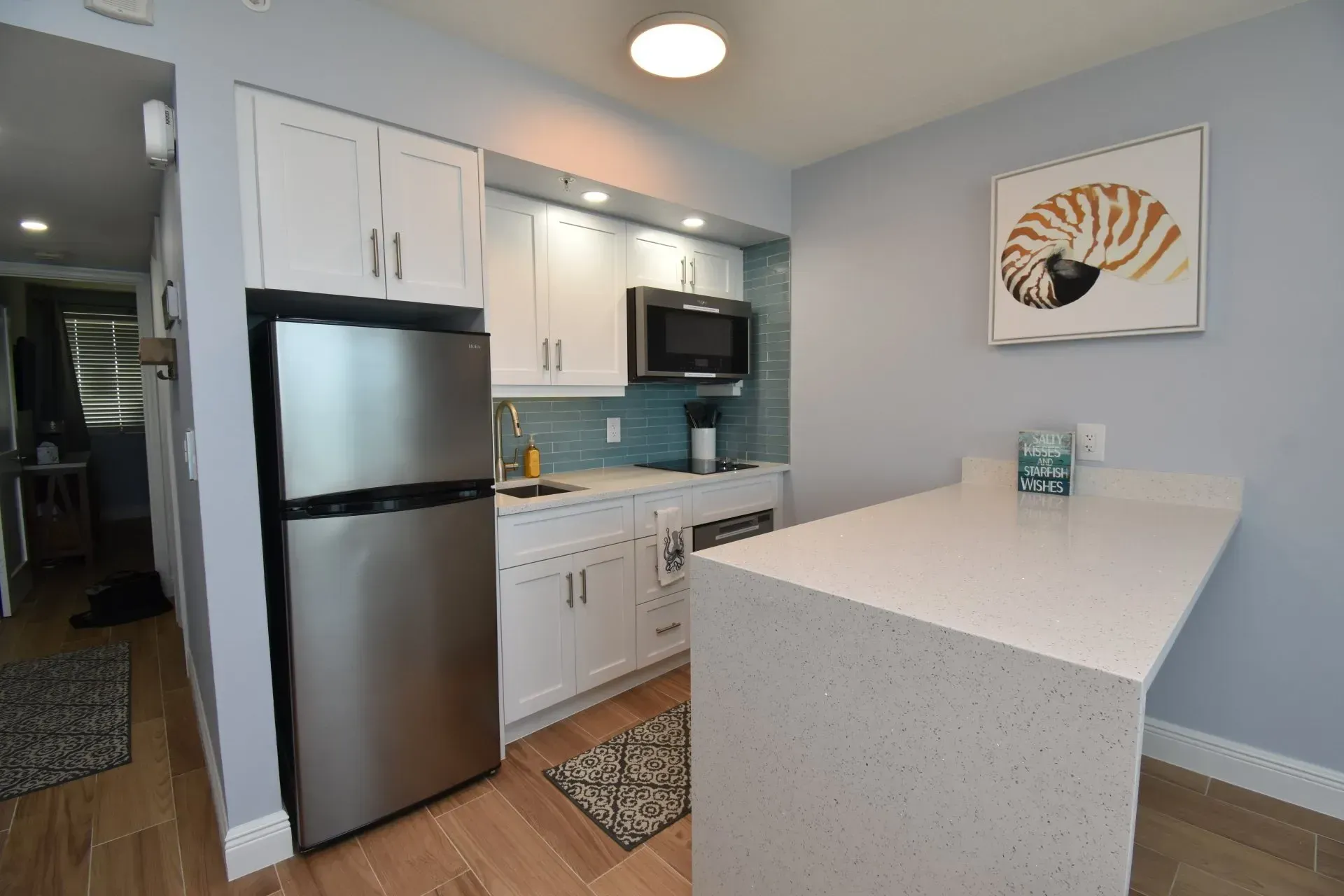 Small kitchen with white cabinets, stainless steel refrigerator, and breakfast bar.