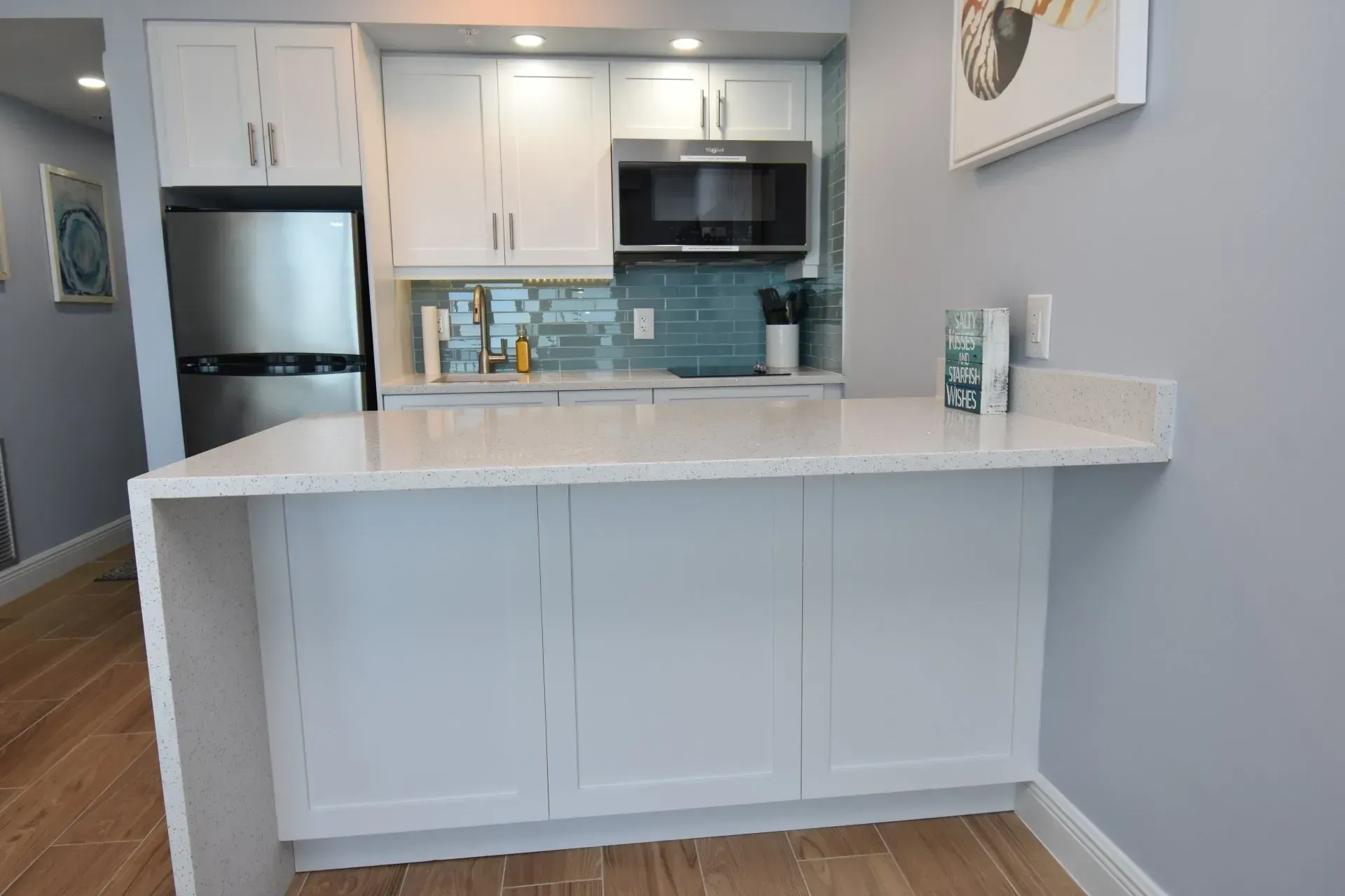 Small kitchen with white cabinets, stainless steel appliances, and a white countertop.