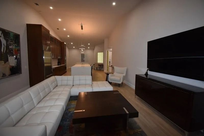 Modern living room with white sectional sofa, dark wood furniture, and large TV.