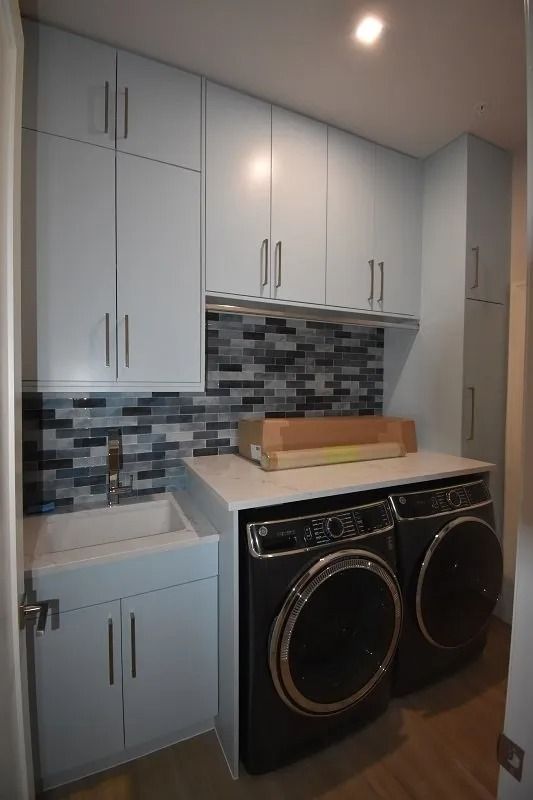 Laundry room with blue cabinets, white countertop, and black washer/dryer.