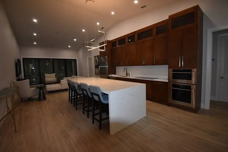 Modern kitchen with island, dark wood cabinets, white countertops, and bar seating.