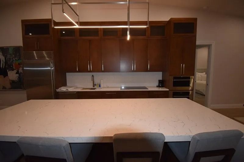 Modern kitchen with dark wood cabinets, white countertop island, stainless steel fridge, and built-in oven.