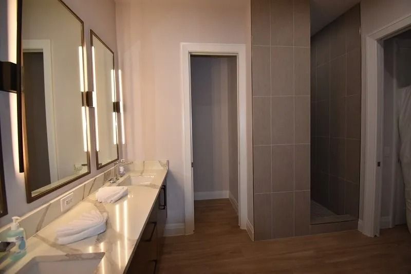 Modern bathroom with dual sinks, large mirrors, and a walk-in shower.