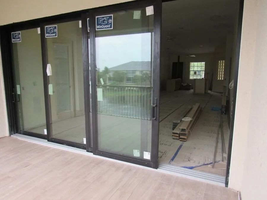 Sliding glass doors on a patio, dark frames, partially open, revealing an interior room under construction.