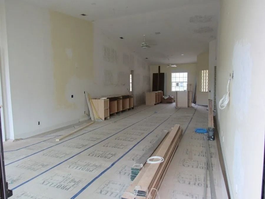 Interior of a room under construction. Cabinets, wood flooring, and exposed walls are visible.