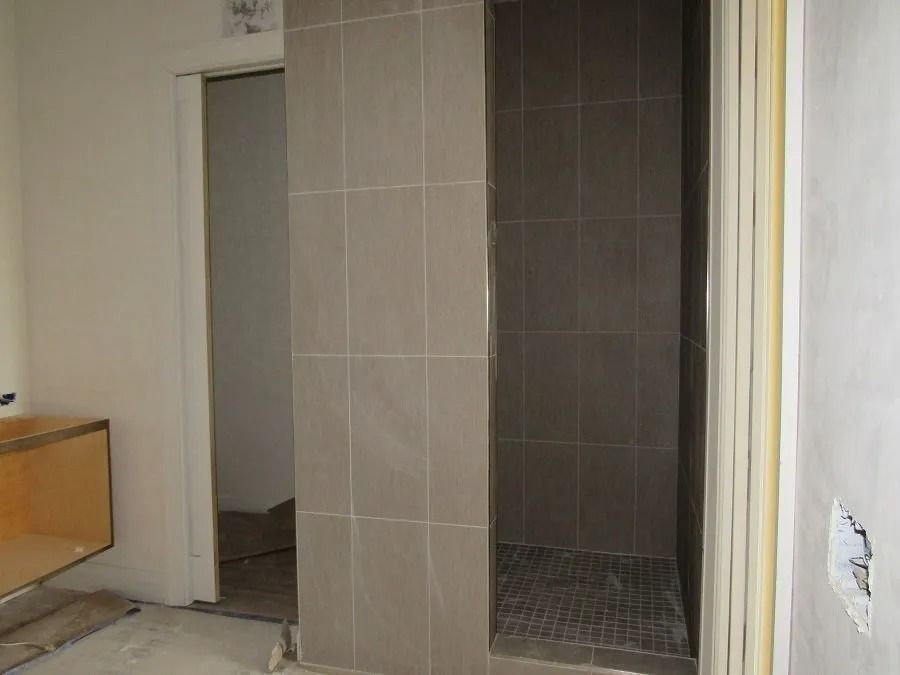 Bathroom under construction with tiled shower and open door.