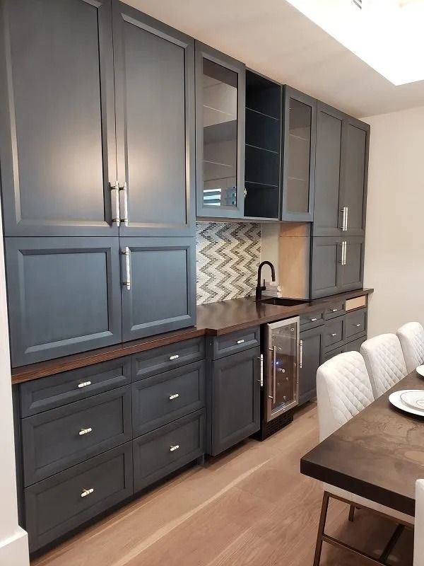Gray built-in bar with cabinets, drawers, wine fridge, sink, and tile backsplash.